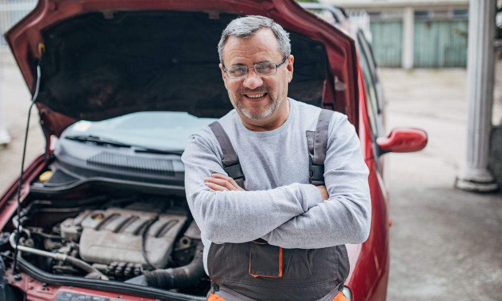 David with Parkinson's disease leasning into open bonnet of car and smiling