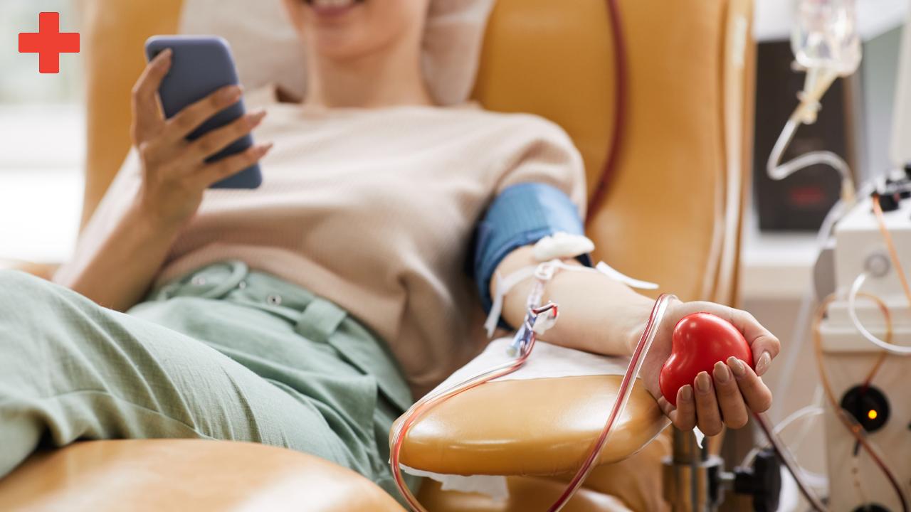 female reclining in cushioned chair while on phone and smiling and blood flowing through tube in her arm