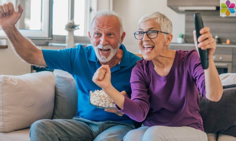 attractive older couple watching TV and cheering
