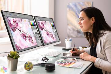 woman sketches while looking at two computer screens of cherry blossoms