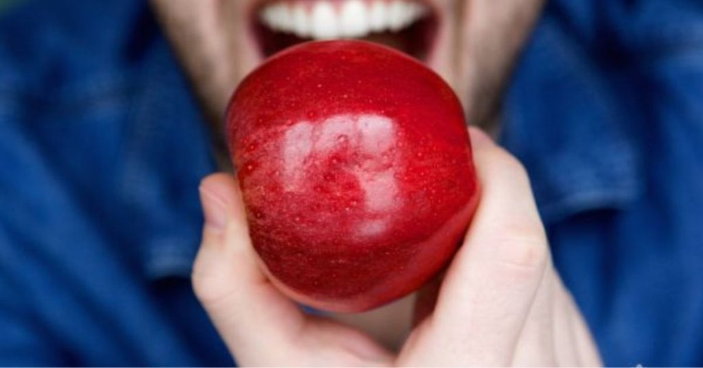 man about to bite into a red apple