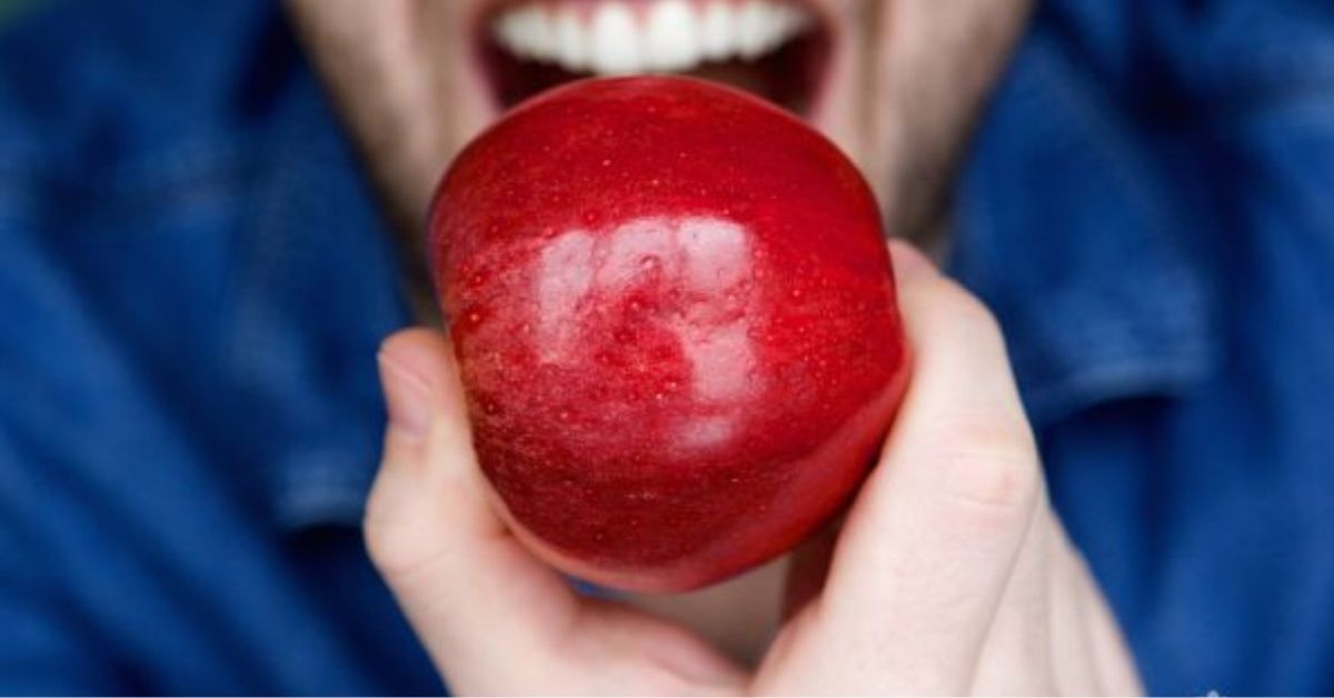 man about to bite into a red apple