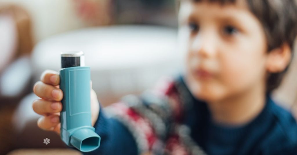 boy extends hand that's holding a blue asthma reliver