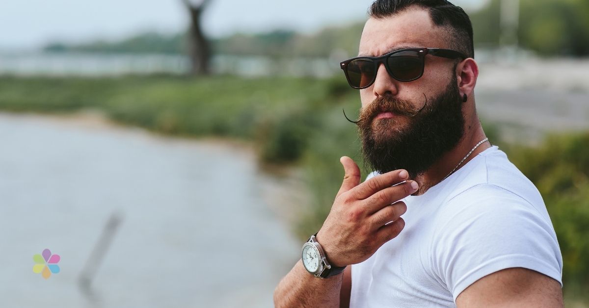 man stroking his lucious beard wearing sunglasses
