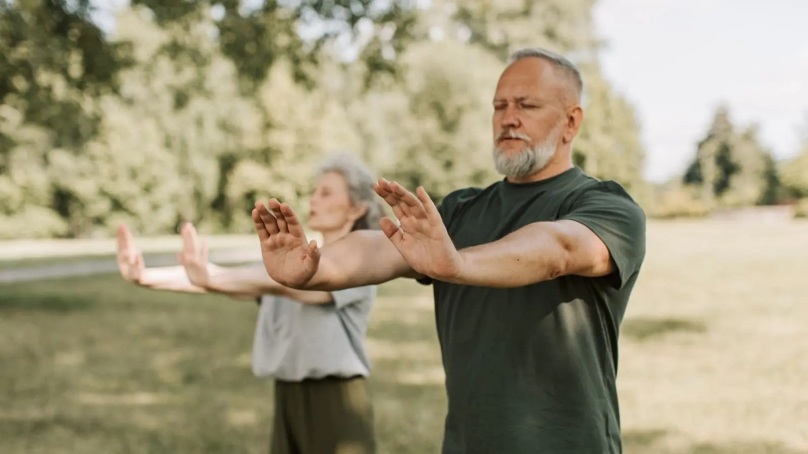 man with hands out and eyes closed outdoors