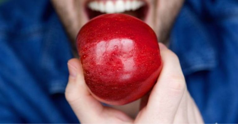 man about to bite into a red apple