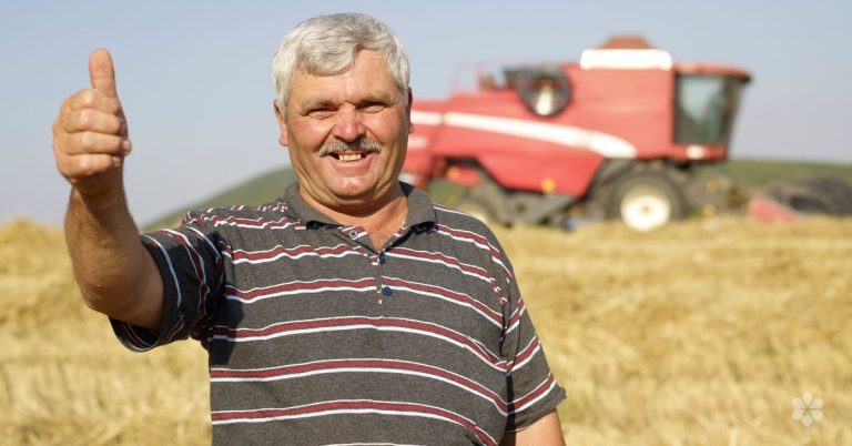man in field in front of tractor gives thumbs up